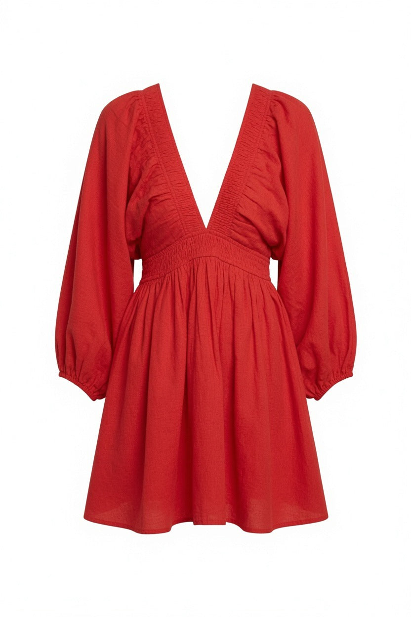 A red long-sleeve mini dress with a smocked bodice, gathered ruffles, and a flared skirt, shown against a plain white background.