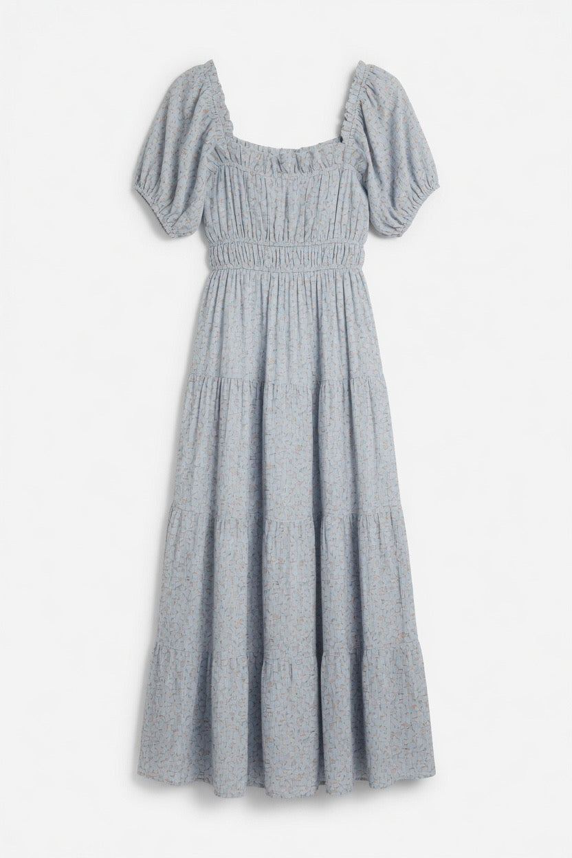 A light blue smocked dress with puff sleeves, a square neckline, and a tiered skirt, shown against a plain white background.