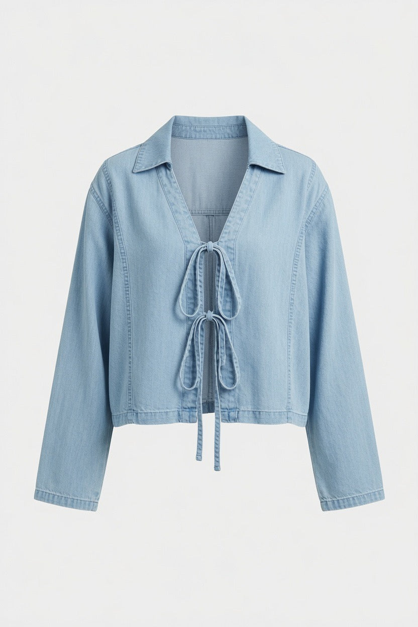 A light blue denim cropped jacket with a tie-front detail, long sleeves, and a pointed collar, shown against a plain light gray background.