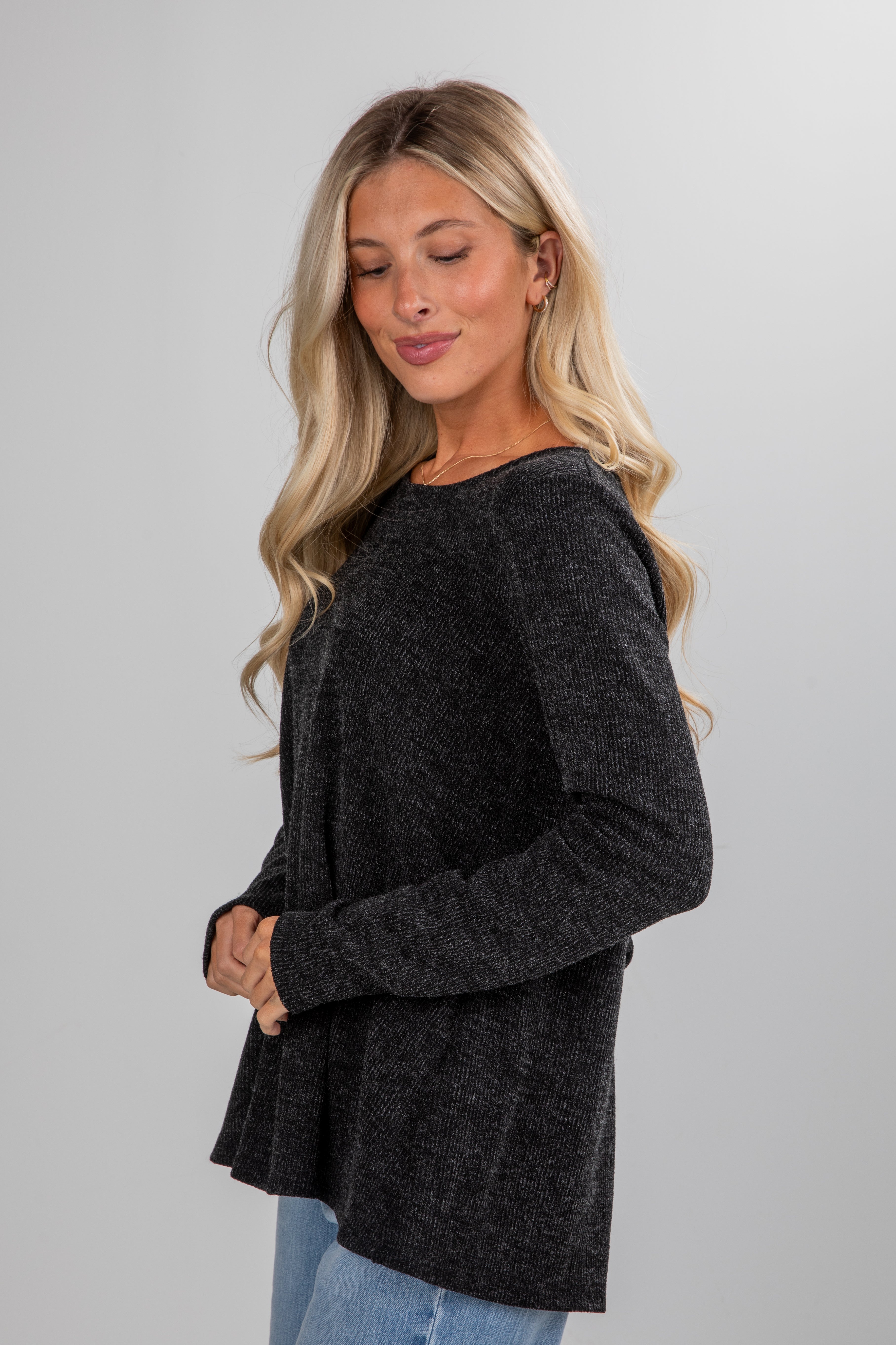 Woman wearing a dark gray sweater against a plain background