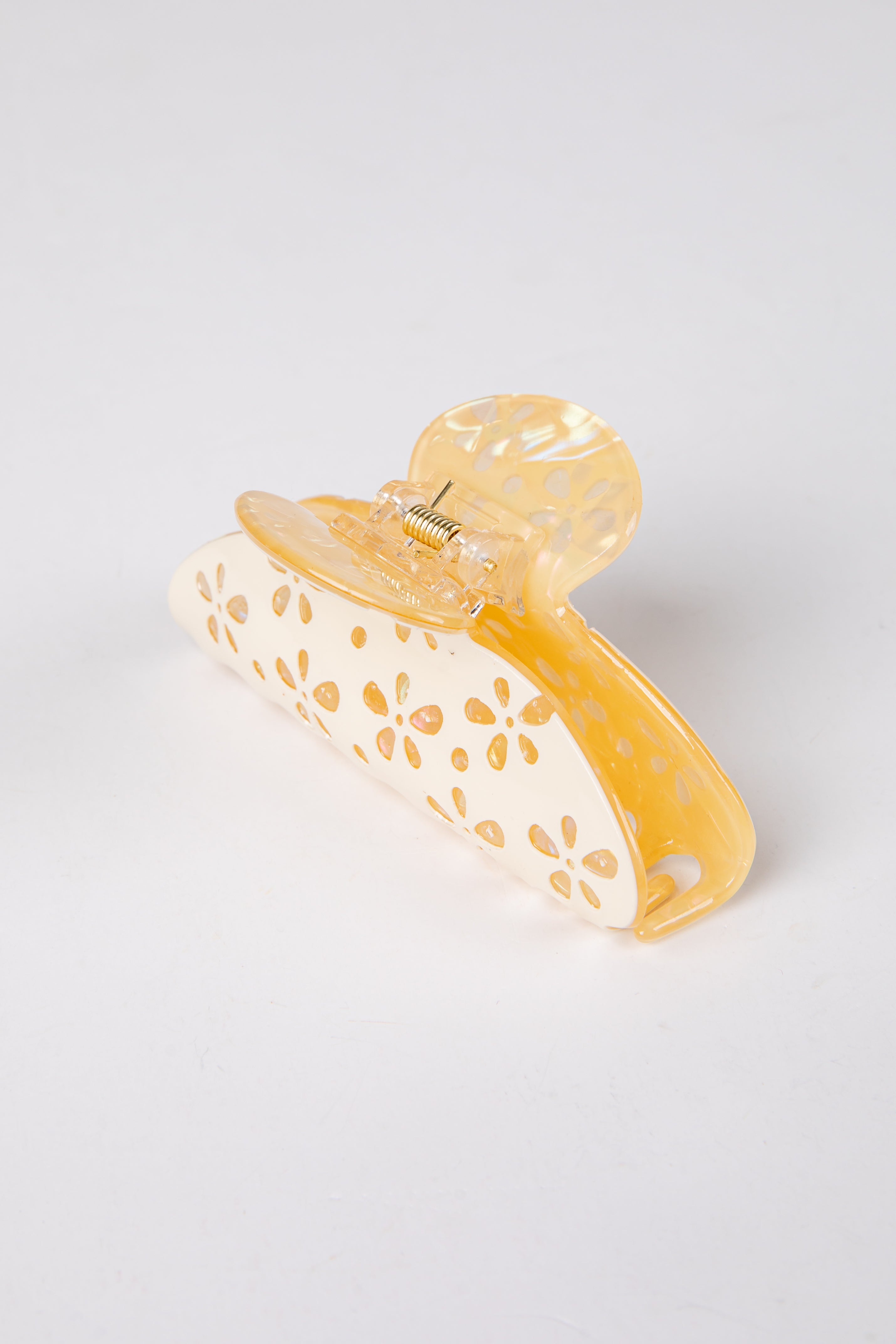 Yellow hair clip with gold accents on a light gray background