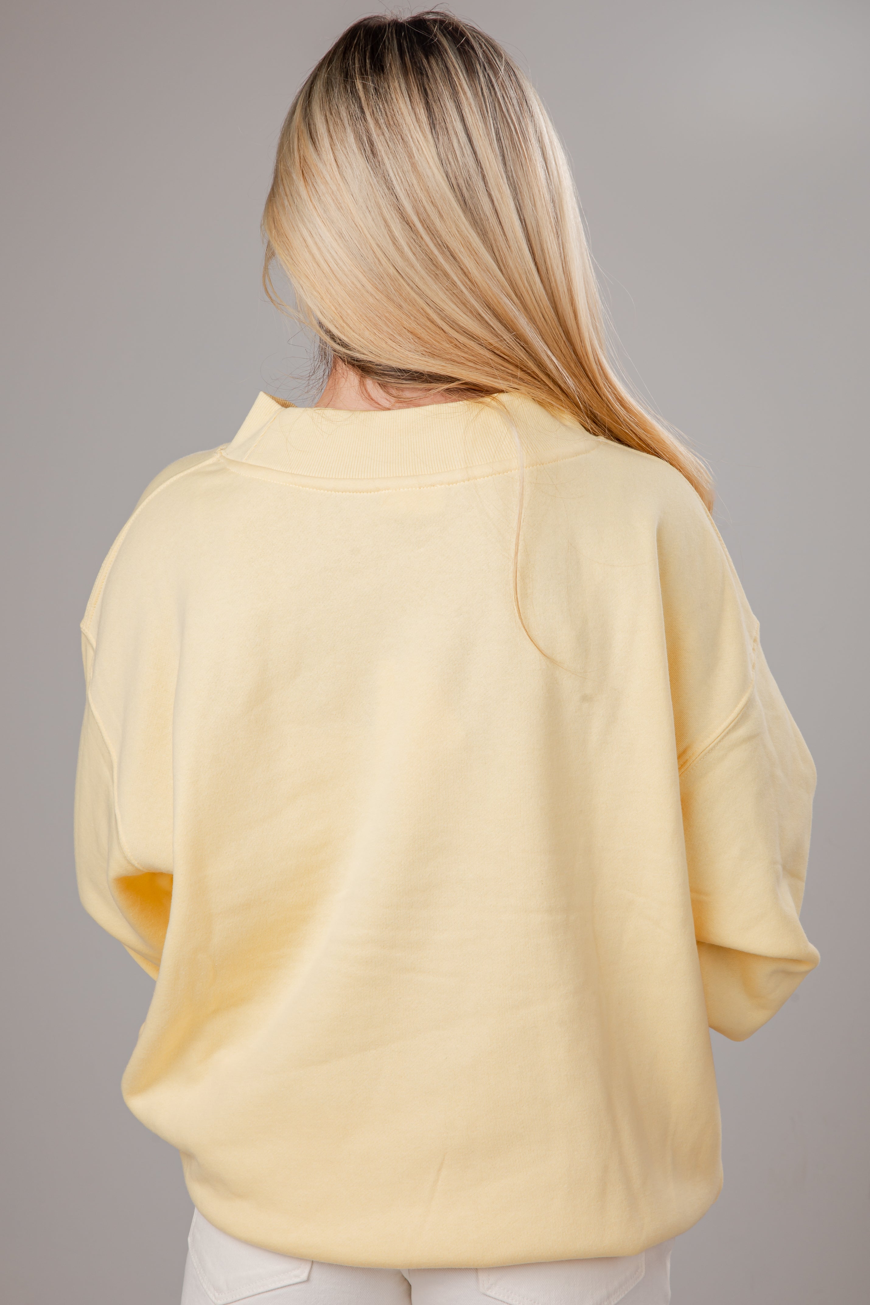 Person wearing a light yellow sweater against a gray background