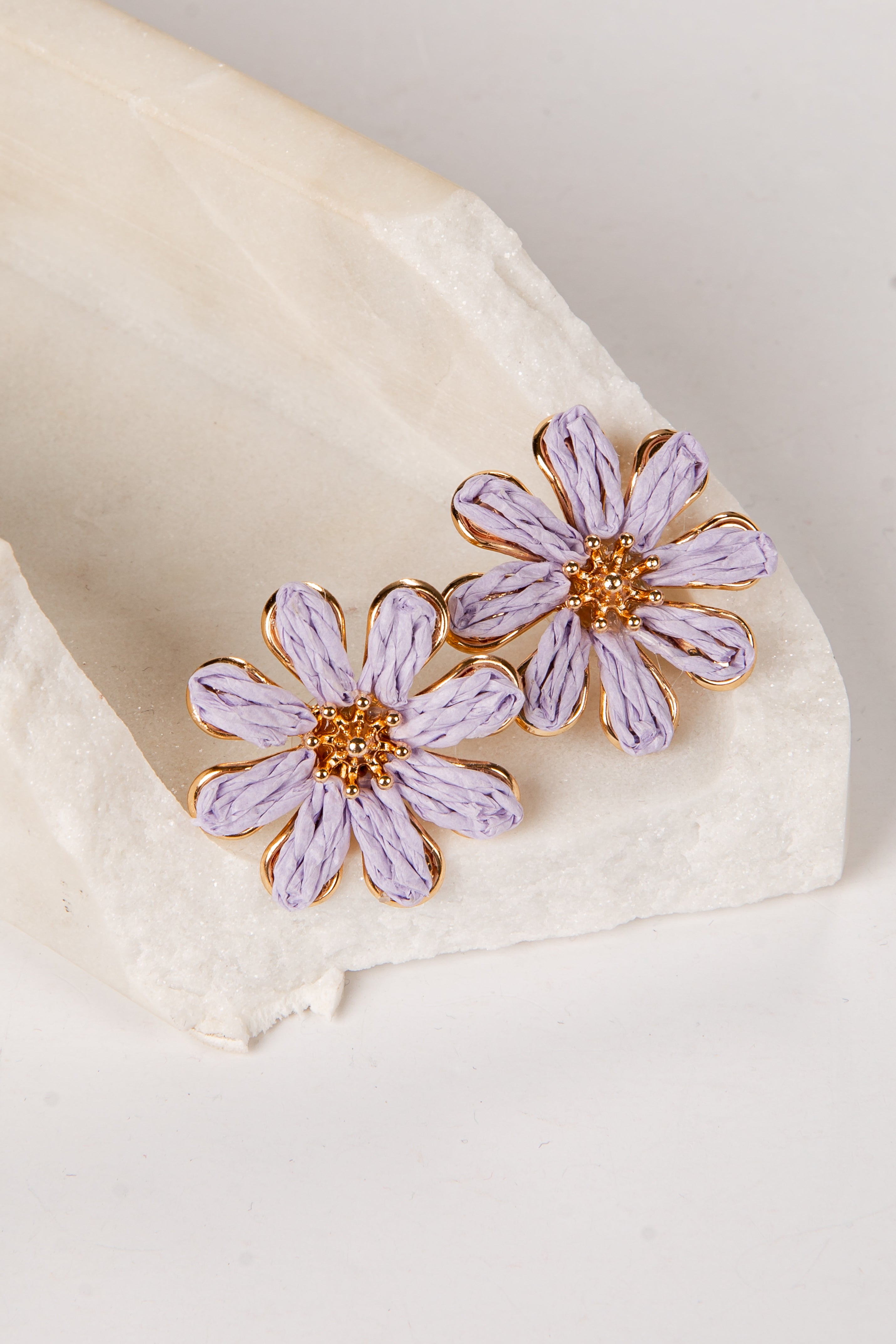 Purple flower earrings on a white fabric background