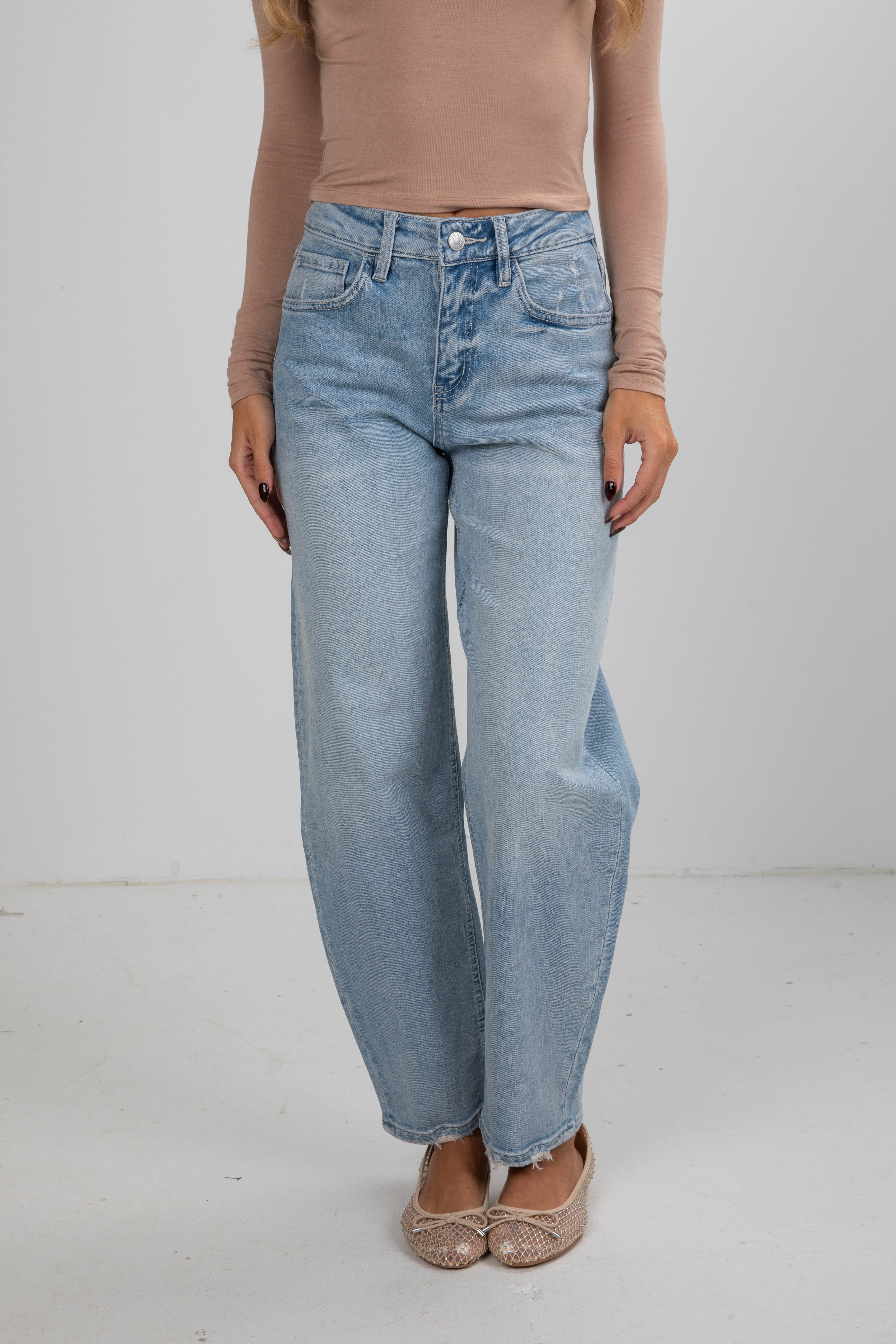 Person wearing light blue jeans and a beige top on a white background