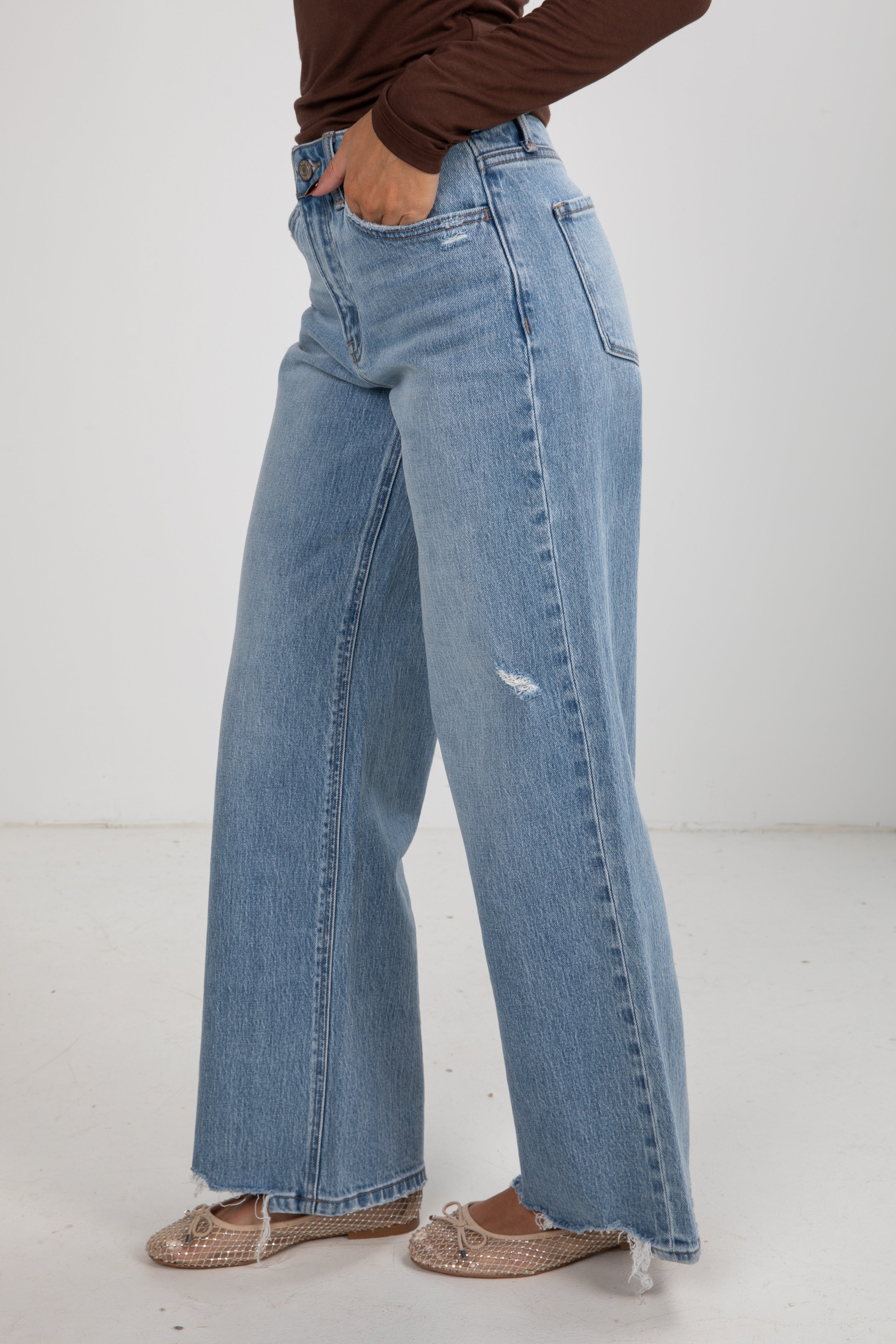 Person wearing light blue jeans on a white background
