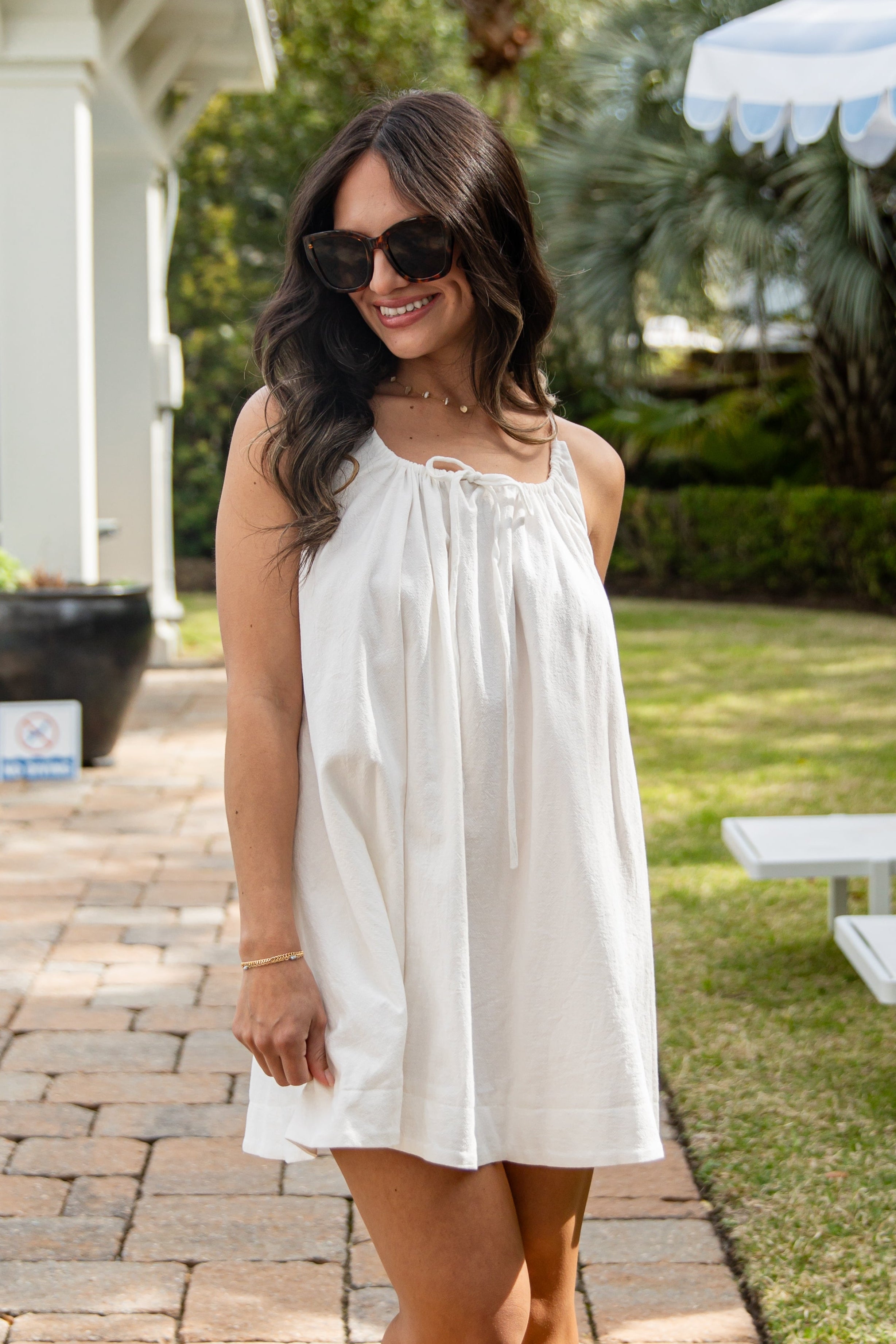 Woman in a white dress standing outdoors on a patio
