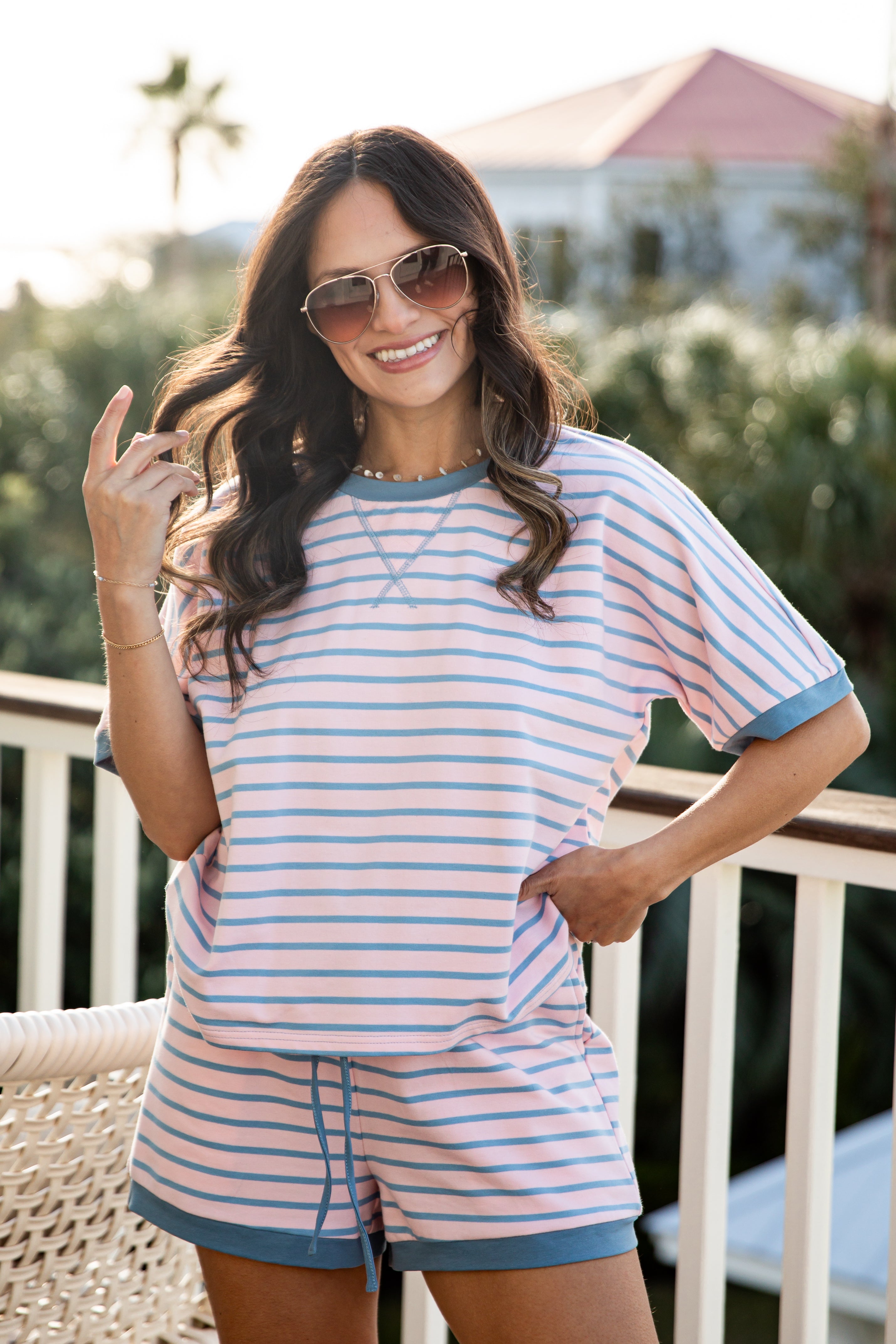Woman wearing a striped outfit on a balcony with a blurred background