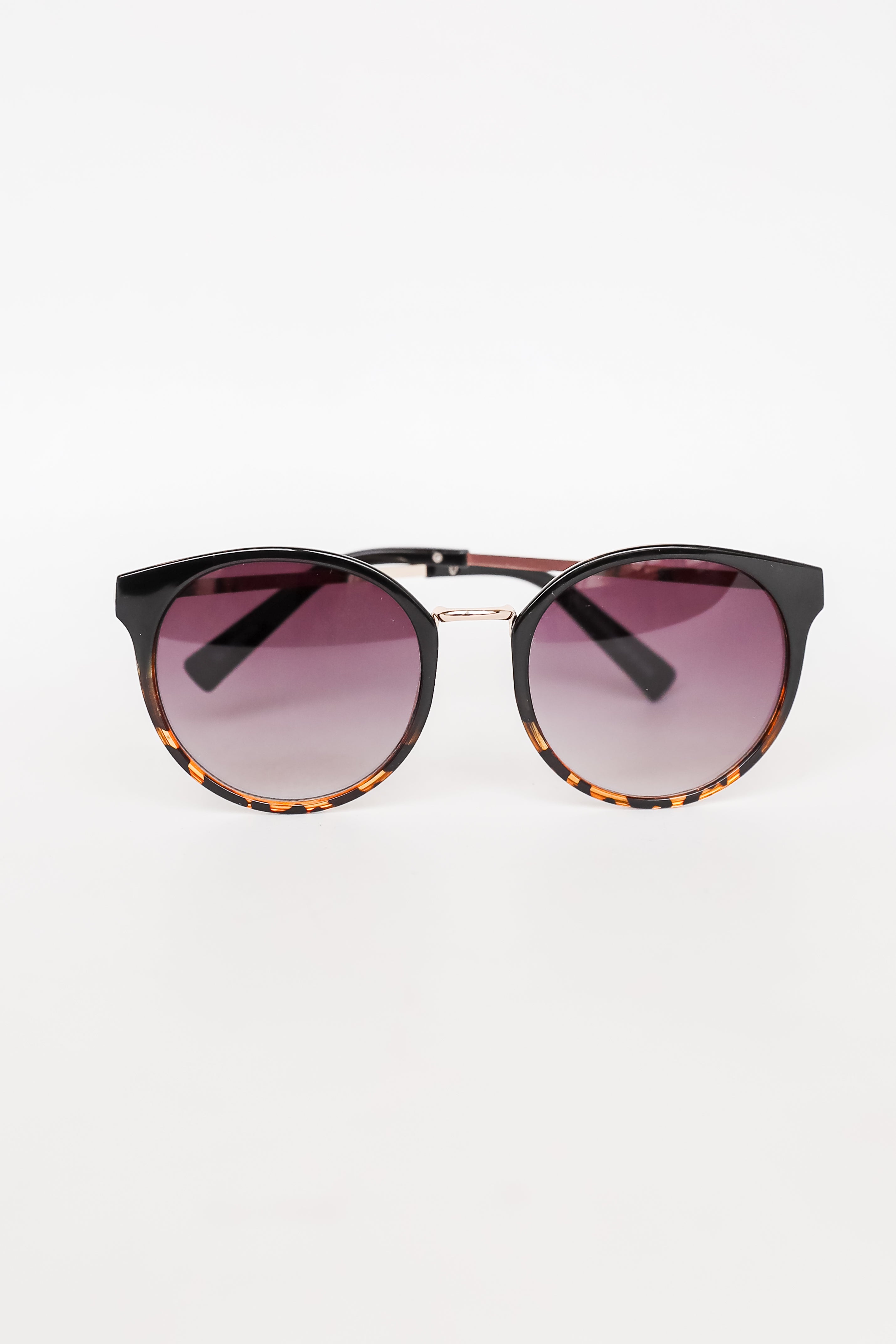 Sunglasses with tortoiseshell frame and gradient purple lenses on a white background
