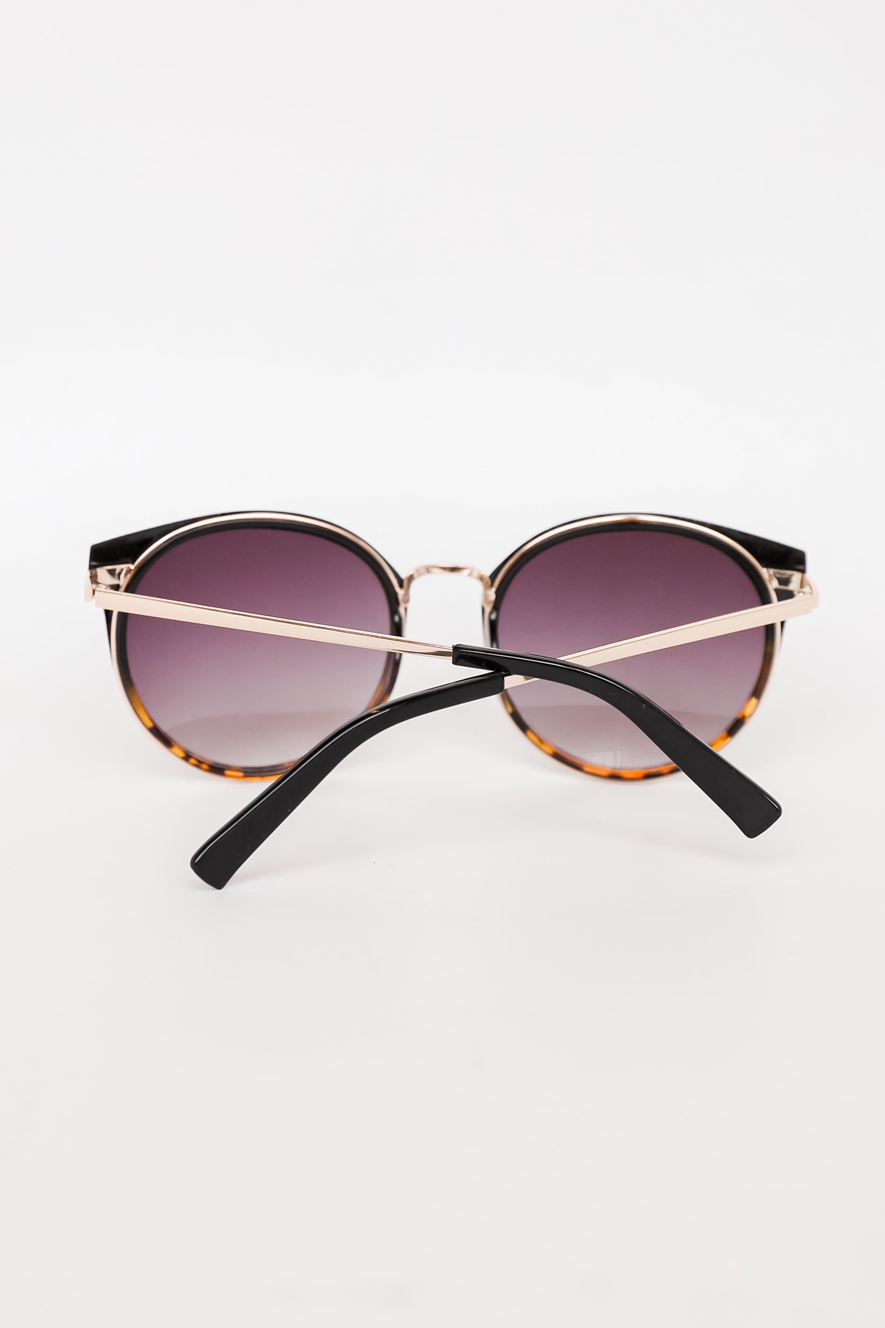 Sunglasses with gold frame and black arms on a white background