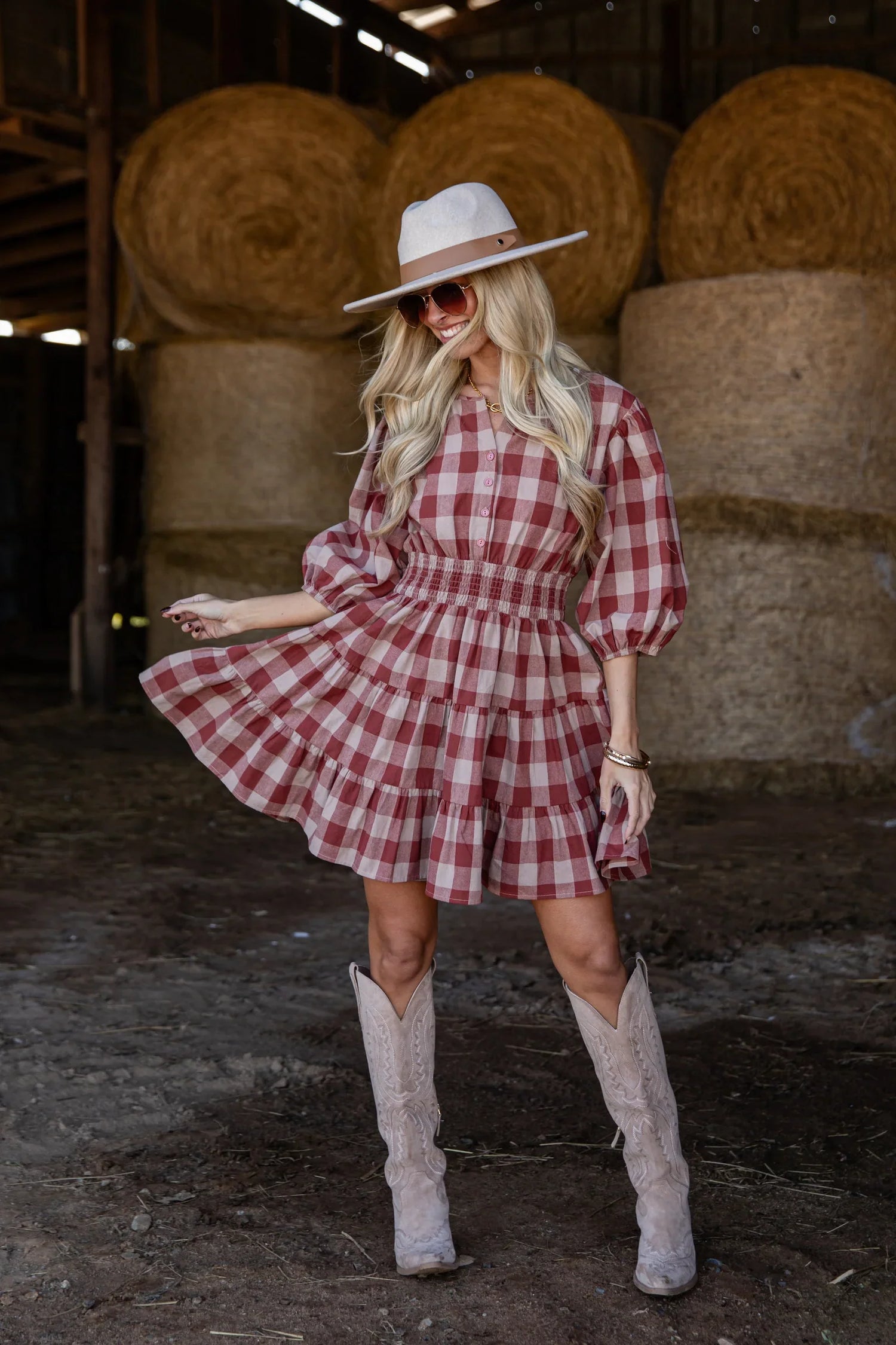 woman wearing a plaid rust red brown dress with boots and a hat. 