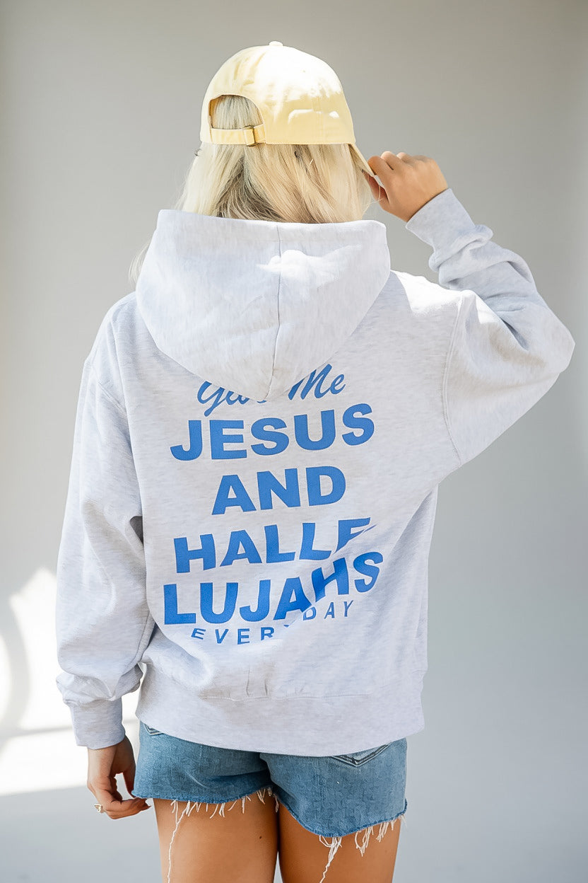 A person shown from behind wearing a light heather gray hoodie with bold blue text on the back reading &