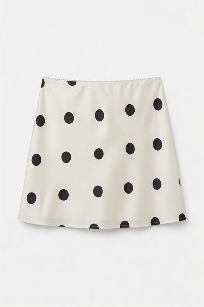 An A-line mini skirt in cream with a black polka dot pattern, displayed flat against a light gray background.
