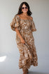 A woman modeling an off-the-shoulder midi dress with a brown and white floral pattern, styled with sunglasses and a bracelet against a light gray studio background.
