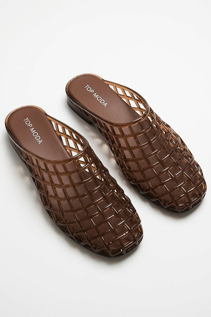 A pair of brown woven mesh mule sandals with a transparent, glossy finish, displayed on a clean white background. The brand name &