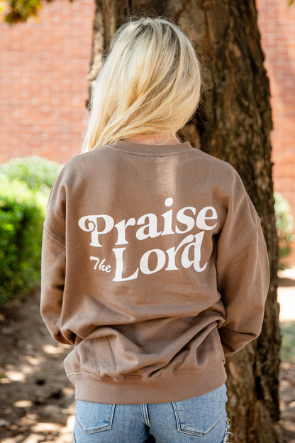 A woman viewed from behind wearing a brown crewneck sweatshirt with &