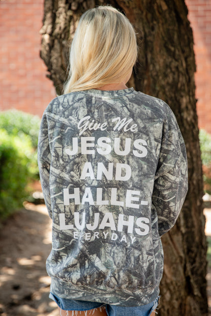 A woman viewed from behind wearing a gray and black camouflage long-sleeve sweatshirt with bold white text on the back reading &