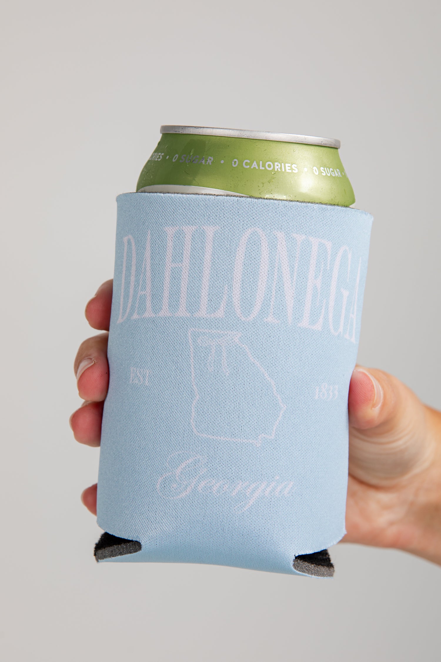 Hand holding a can with a blue sleeve featuring &