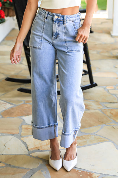 Person wearing light blue jeans and a white top on a stone patio.