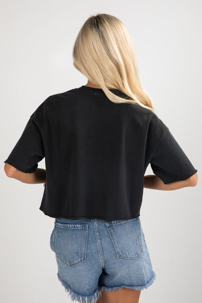 Person wearing a black t-shirt and denim shorts on a plain background