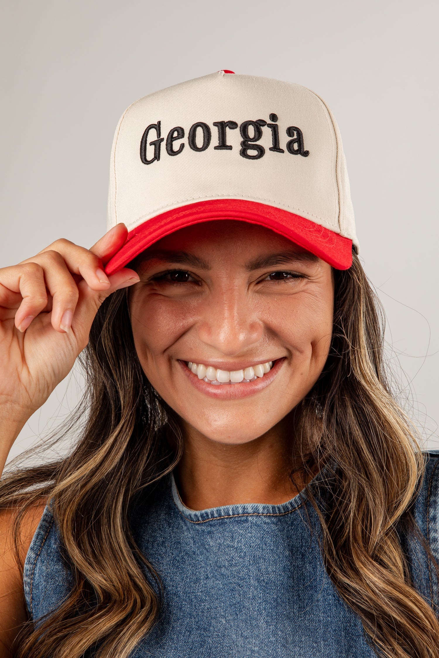 Woman wearing a beige and red cap with &