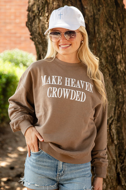 A woman wearing a brown crewneck sweatshirt with the text &