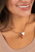Close-up of a woman wearing a gold necklace with charms.