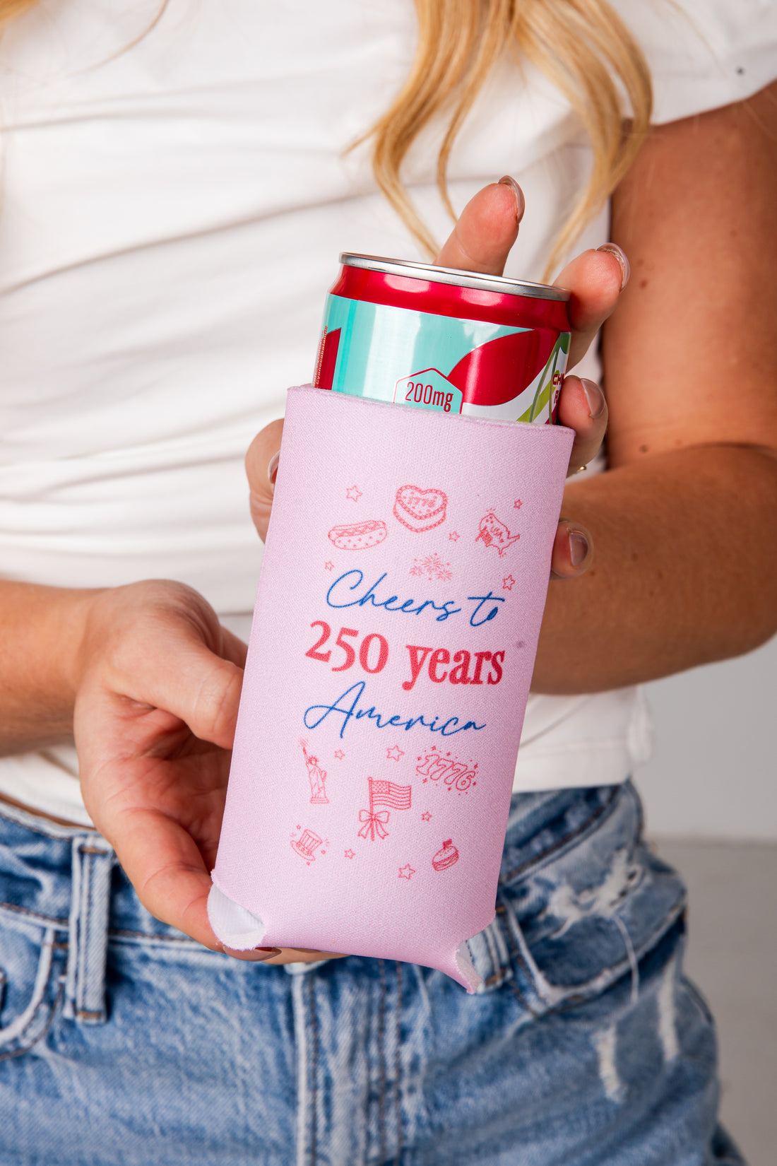 Person holding a can with a pink sleeve that says &