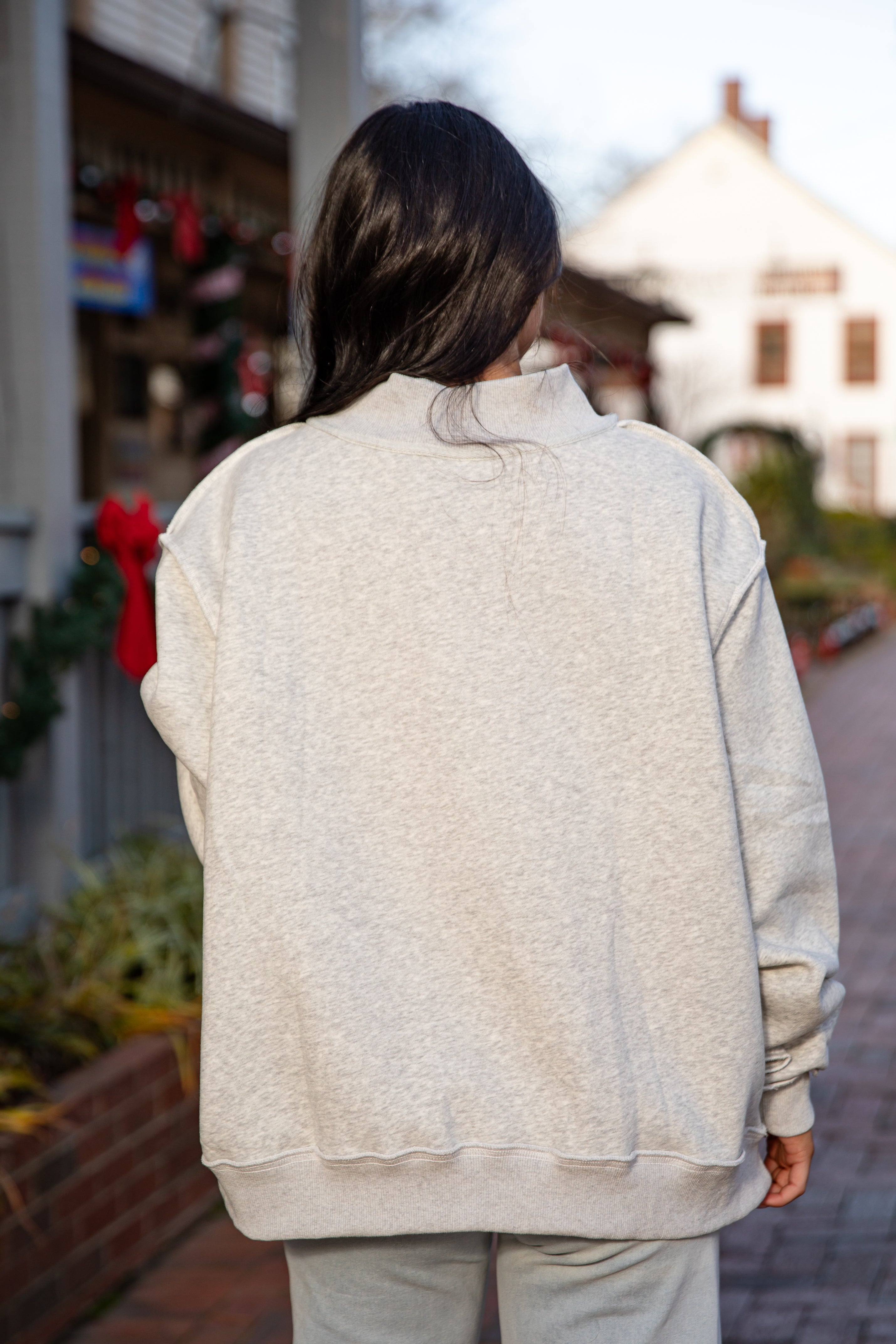 Person wearing a light gray jacket walking outdoors with a blurred background