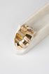 A wide statement ring with alternating polished gold and iridescent white mother-of-pearl segments, displayed on a white marble stand against a clean white background.