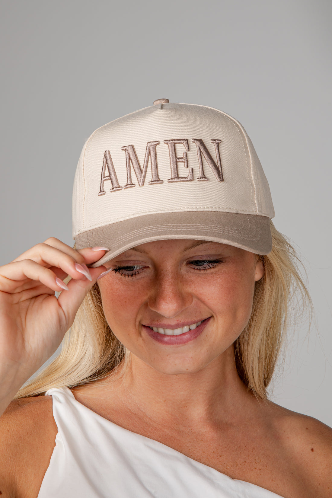 A woman wearing a beige baseball cap with &