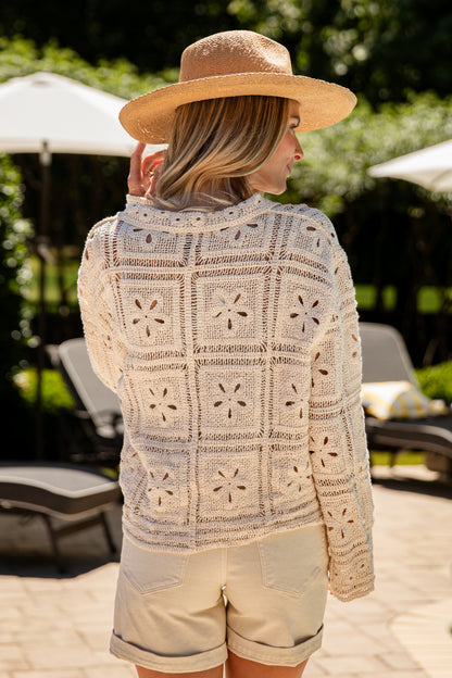 Woman wearing a patterned sweater and straw hat in an outdoor setting