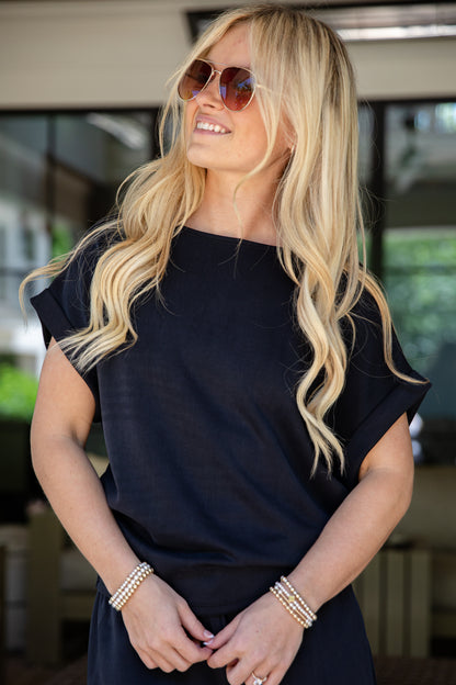 Woman wearing sunglasses and a black outfit with a blurred background