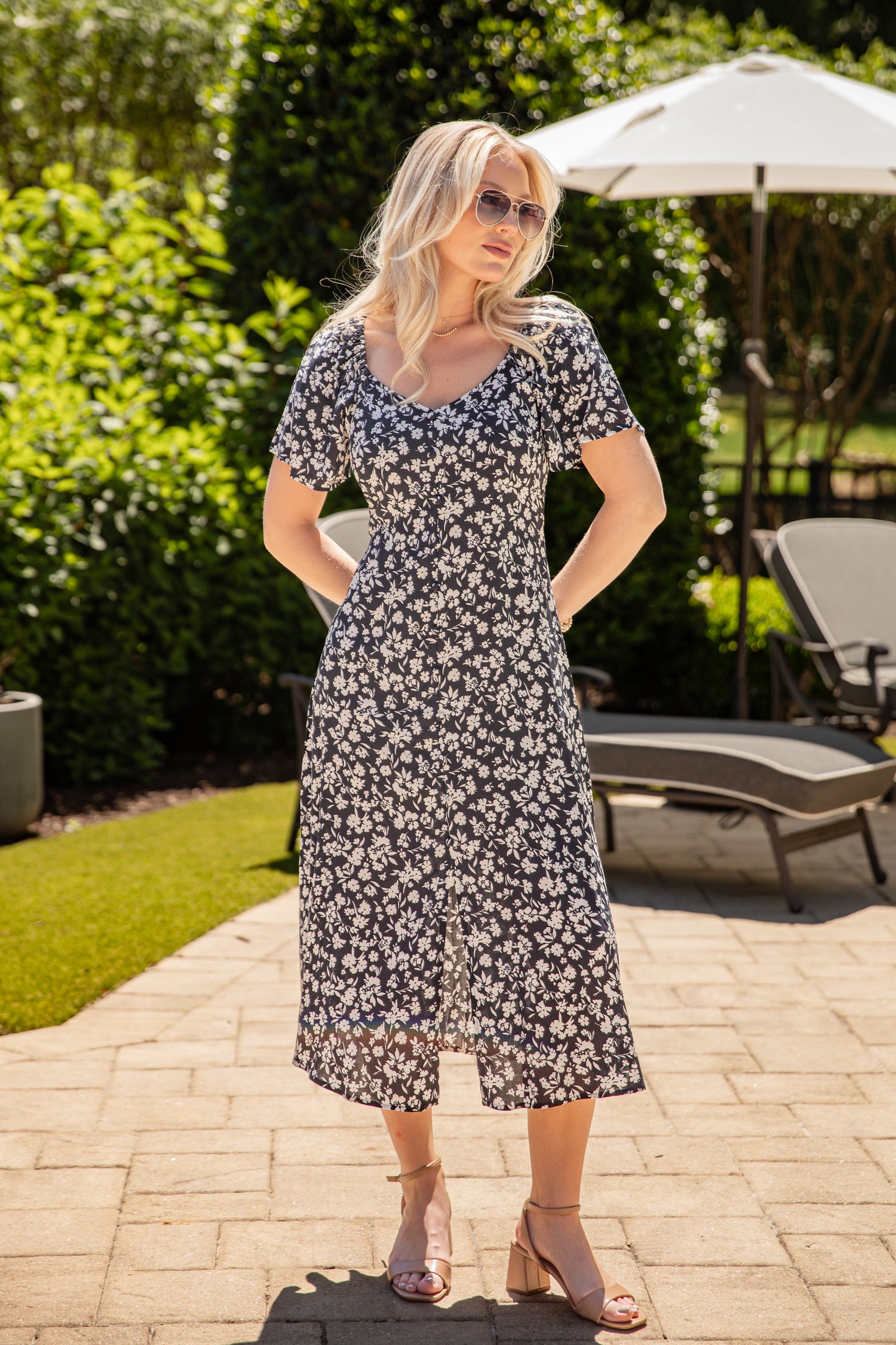 Woman in a floral dress standing outdoors on a patio
