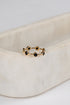 Gold ring with black stones on a beige fabric background