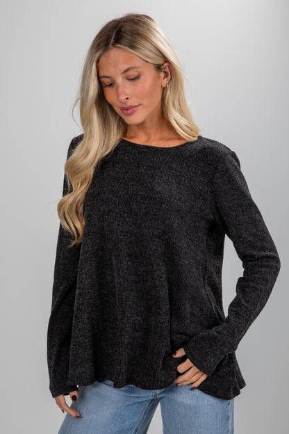 Woman wearing a black sweater and blue jeans on a gray background