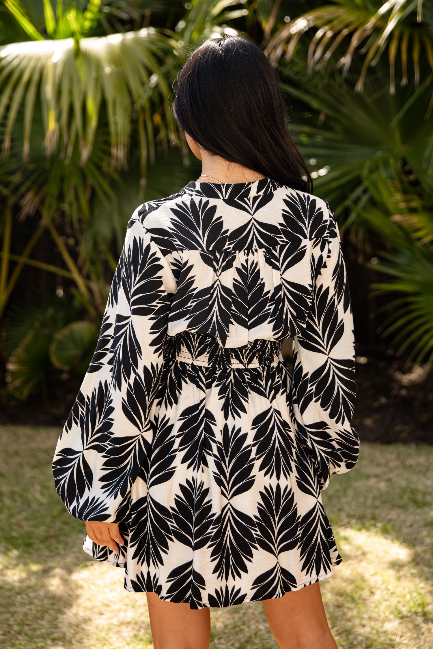 Person wearing a black and white leaf pattern dress in a garden setting