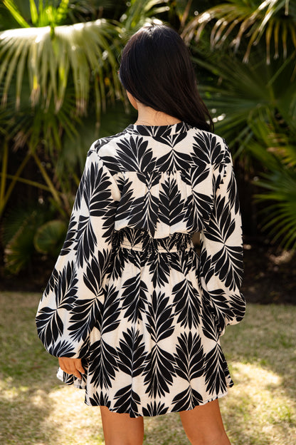 Person wearing a black and white leaf pattern dress in a garden setting