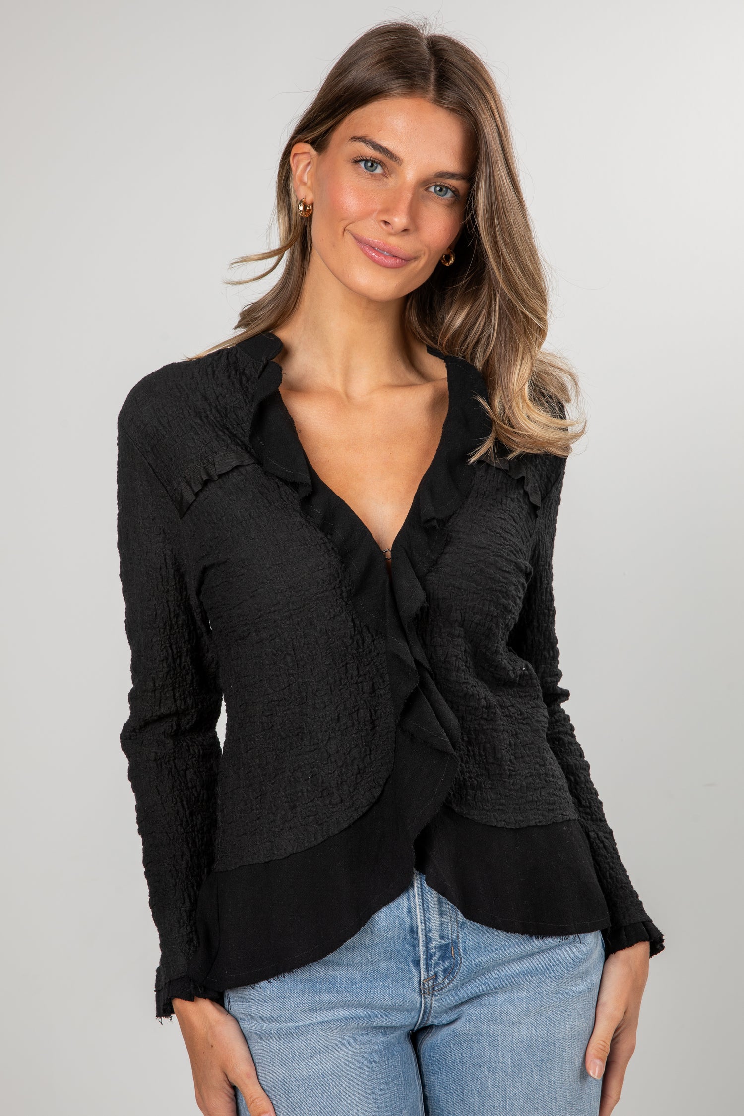 Woman wearing a black jacket and blue jeans on a plain background