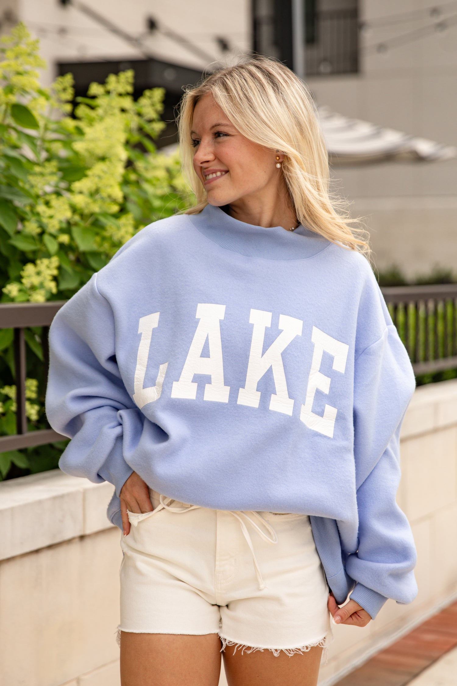 Woman wearing a light blue sweatshirt with &