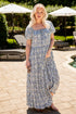 Woman in a floral dress standing outdoors near a pool area