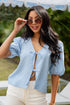 Woman wearing a blue checkered shirt and sunglasses outdoors