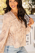 Woman wearing a beige floral blouse and blue jeans outdoors.