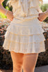 White lace dress with ruffled layers worn by a person, blurred background