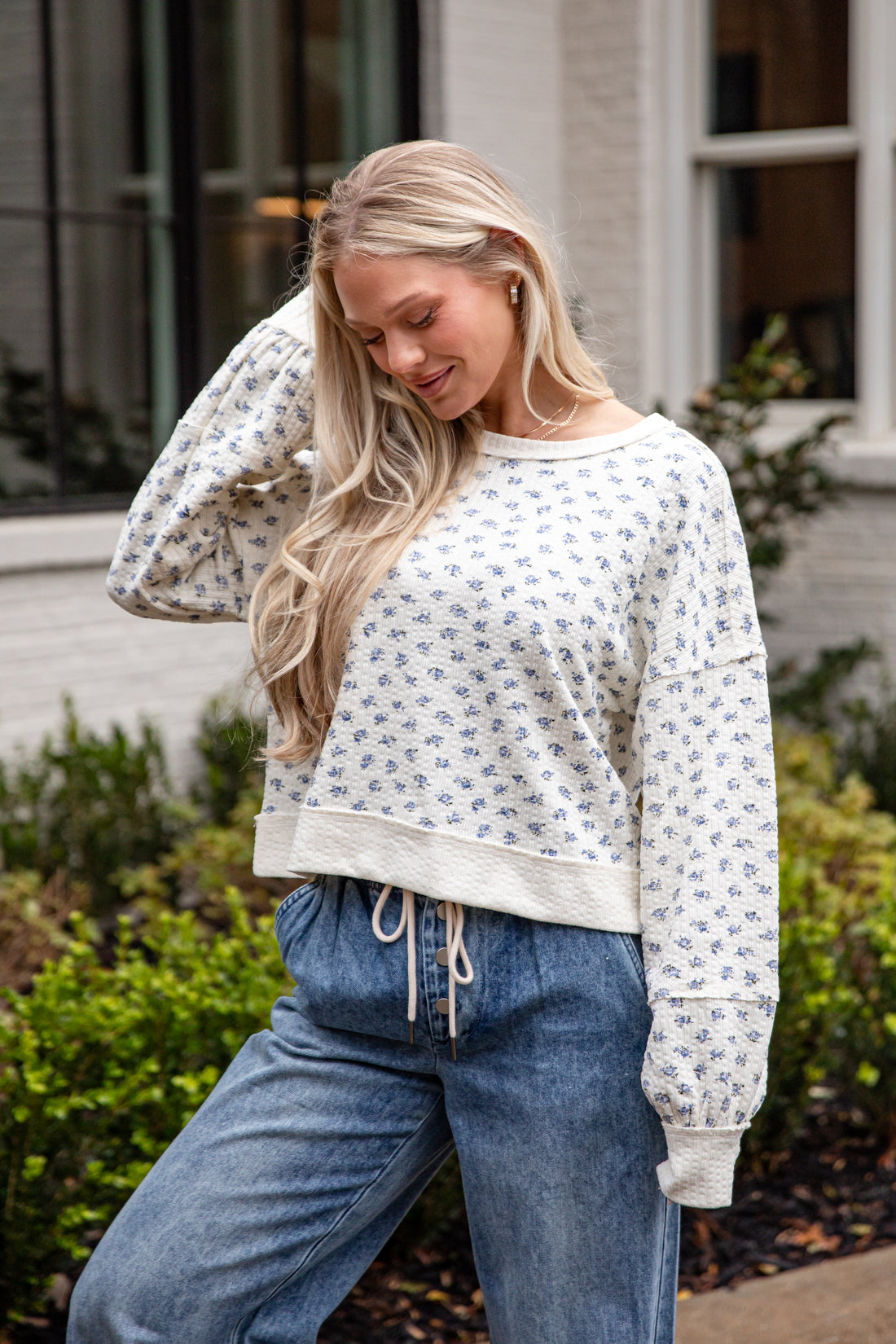 Woman wearing a patterned sweater and blue jeans outdoors.