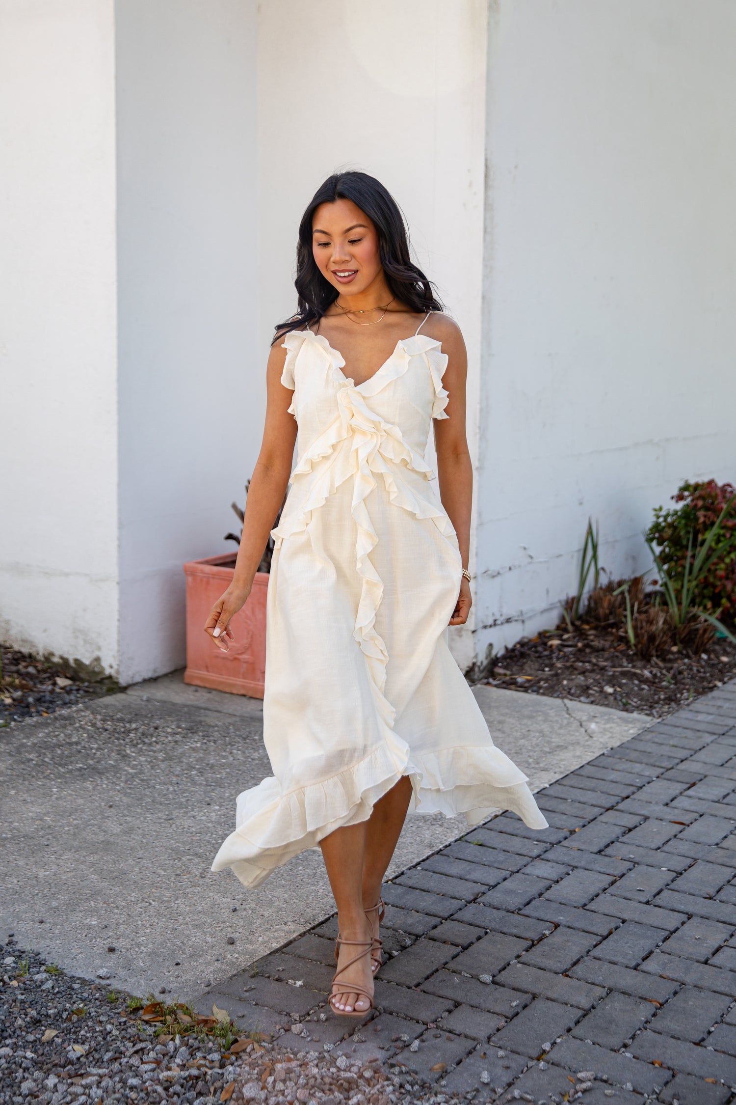 Woman in a white dress walking outdoors on a sunny day.