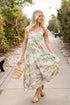Woman in a floral dress walking along a path in a park.