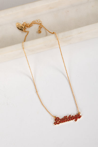 Gold necklace with red lettering on a white surface