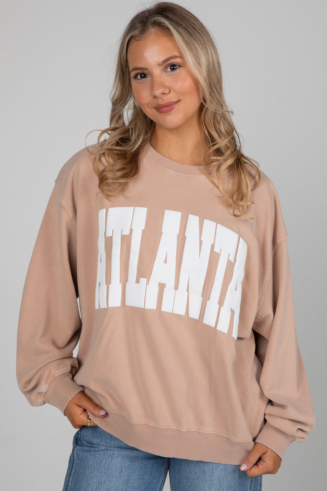 Woman wearing a beige sweatshirt with &