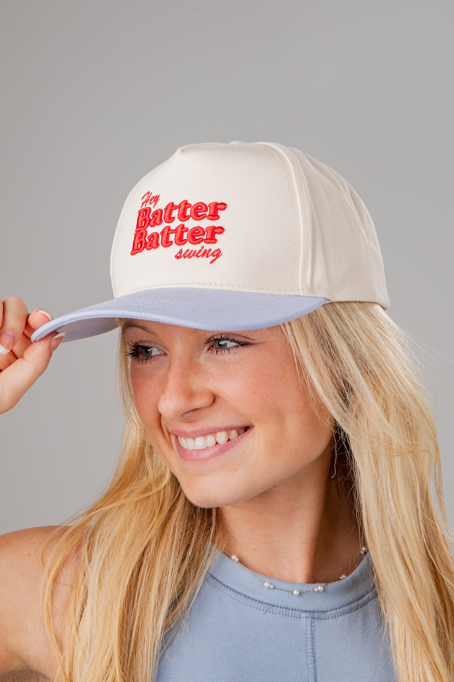 Woman wearing a white cap with red text on a gray background