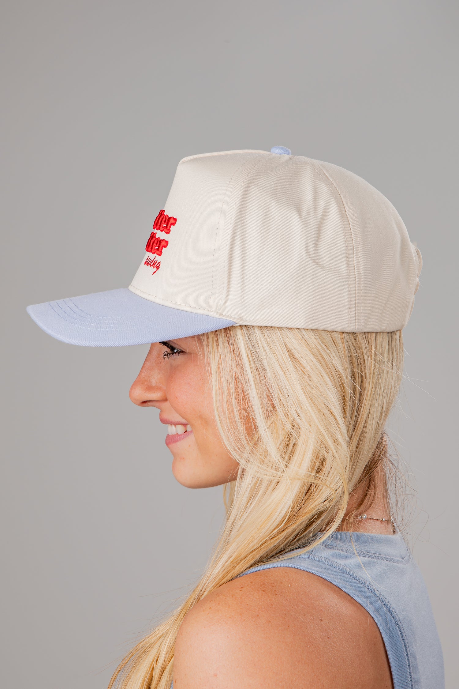 Woman wearing a beige cap with a red logo on a gray background